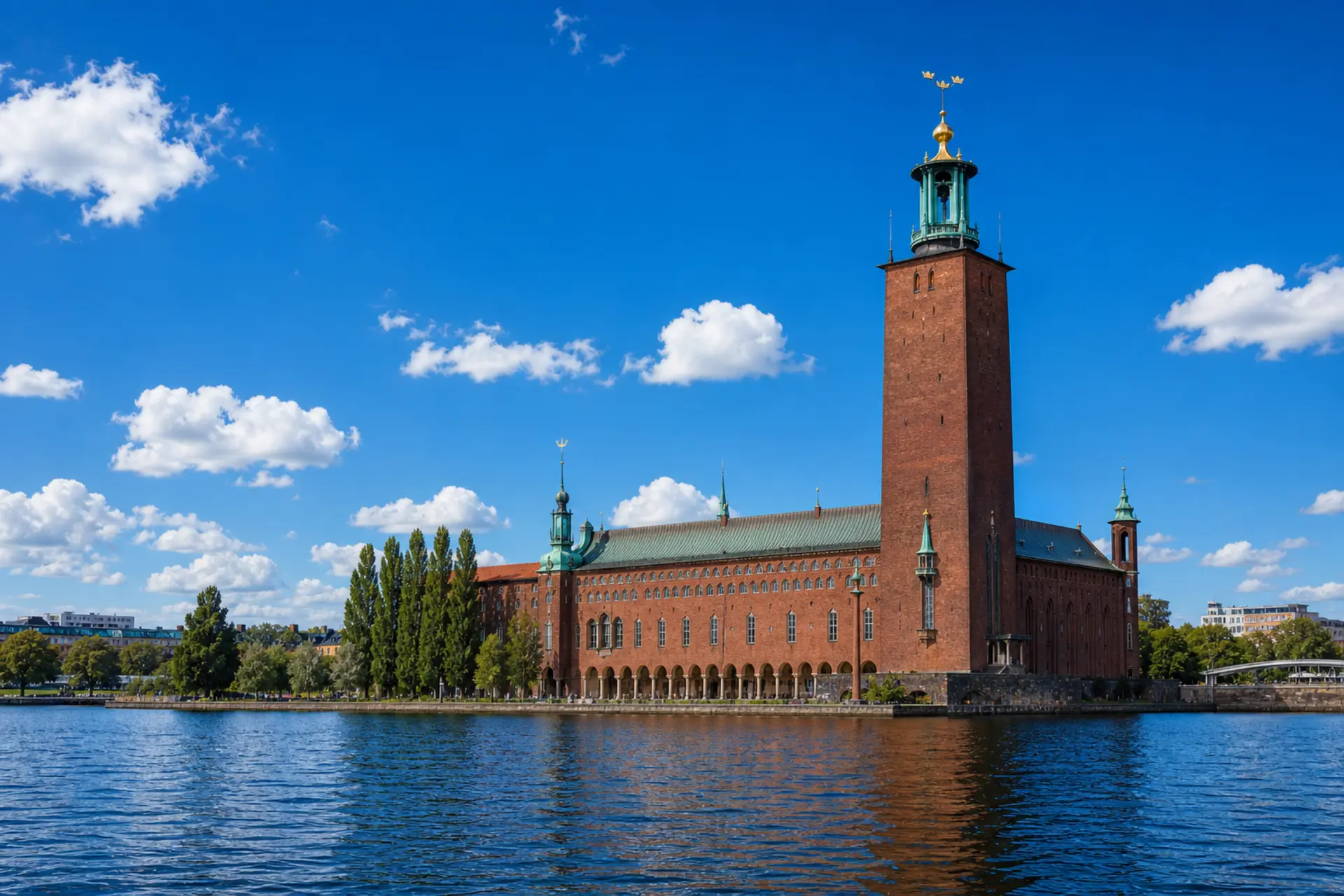 Cihlová věž stockholmské radnice Stadshuset se třemi zlatými korunami nad vodou